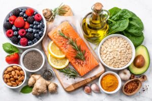 Fresh anti-inflammatory foods including berries, salmon, oats, olive oil, leafy greens, and spices arranged on a clean kitchen surface